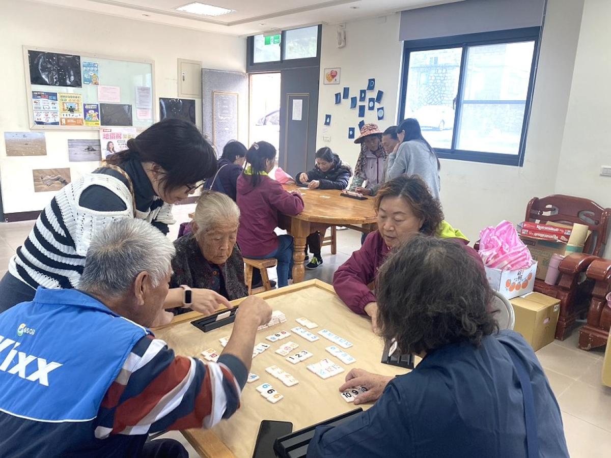 長者們投入拉密牌遊戲，專注排列牌組、互相討論策略，現場洋溢歡樂氣氛。