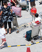 把行李推車當娃娃車很危險,港務處呼籲旅客切勿將小孩放置於推車上。(圖/文:劉秋月)