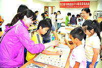　「100年親子FUN暑假系列活動」歡樂登場，首場活動為「親子烘焙屋－甜點DIY」，請烘焙師葉寶玲指導蛋塔、菊花小西餅的製作，親子們互動熱絡。（圖／文：曹重偉）