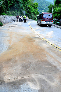 福澳村復國路昨天又發生機油外漏污染道路事件,縣警局出動員警維護交通秩序,環保局人員也努力清理油漬,以確保行車安全。(圖/文:曹重偉)