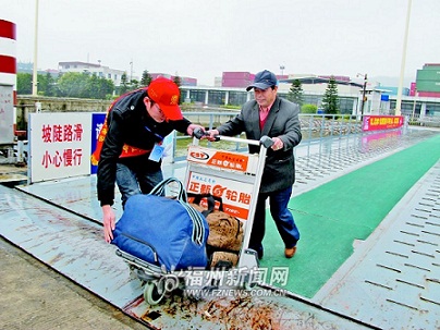 回家過年的馬祖鄉親在福州港馬尾客運站通關後推行李登船,春運志願服務者在場協助。(圖:福州日報記者林穎文攝)