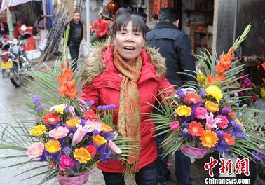 農曆除夕，著名僑鄉福建連江縣琯頭鎮花市生意十分紅火，受到當地村民以及海外歸來歡度春節的華僑、華人青睞。圖為村民歡喜購得鮮花回家過年。中新社發劉可耕攝
