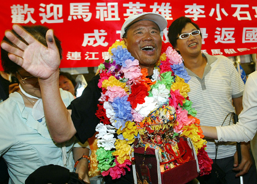 圖為2009年李小石(中)揹著媽祖金身攀登世界第1高峰聖母峰挑戰成功後,順利返抵國門。(圖/ 聯合報系資料照)
