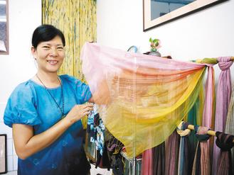 洪靜文在自宅成立「三分顏色」工作坊,手中展示的絲巾是得意作品之一,歷經多道工序才有繽紛成果。 記者徐白櫻/攝影