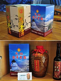 馬祖酒廠3公升罈裝老酒去年換新裝,從原先的國畫古典風格,轉換成融合東引燈塔的碧海藍天及北竿芹壁的思古幽情,展售部展示櫃上的罈裝老酒也換成新包裝。(圖/文:曹重偉)