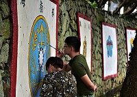 輝煌的傳奇時代豈能一筆就勾消！東引幹訓班舊址牆上有14面部隊隊徽，超過大半單位都已經告別光榮歲月，走入歷史。兩位年輕阿兵哥拿著畫筆，小心翼翼地為褪色的隊徽擦上新漆，官、兵心裡都明白：無論再怎麼求新求變，傳奇永遠不會退流行。 （圖與文：陳其敏）