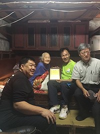 牛角百歲人瑞劉春蓮與劉增應、謝春福、陳振國轉送總統府寄贈禮品,並合影留念。(圖:南竿鄉公所提供)