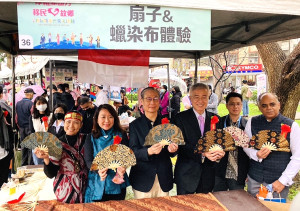 十大優秀新住民、外籍人士及移工與移民署署長鐘景琨(右六)與桃園市副市長李憲明(右七)大合照。移民署署長、桃園市副市長及印尼代表處專員一同逛桃園新市集攤位,體驗手作印尼蠟染扇子。(圖:移民署)
