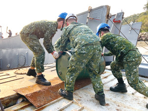 官兵協力將油桶推行上船。(圖:簡慈儒)