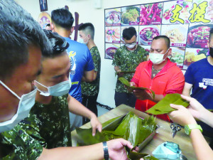 官兵相互教學粽葉摺法。（圖：陳君瑜）