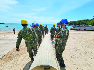運輸連官兵搬運灘岸載運所需之塑膠蓆。（圖：程婉琳）