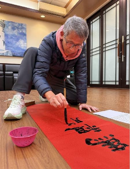 行政處邀請書法高手王建華現場揮毫，為縣府大樓量身手書新春門聯，以遒勁筆觸為縣府注入新年蓬勃氣象。（圖／文：王致潔）