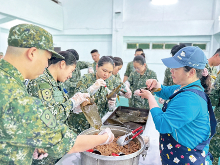 志工媽媽示範包粽技巧，官兵專注學習。