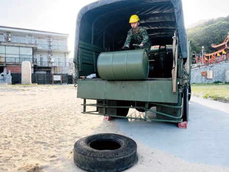 官兵將實桶油桶於車上推行下車。