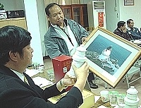縣長陳雪生仔細端看東引酒廠所開發設計的東引燈塔百週年紀念酒樣品,並拿來與燈塔照片相對照。(圖/文:陳其敏)