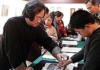 　文化局舉行「黃書墩篆刻書法陶刻展」，圖中黃書墩現場為小朋友示範拓印的過程。（圖／文：張登傑）