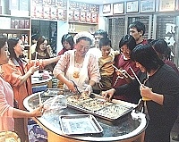 大家齊心製作的迷你糕出爐啦!只見學員們手拿筷子興奮的擠成一團,林蓮花老師看見大家這麼捧場也樂得笑開懷。(圖/文:曹重偉)