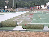 　塘岐運動場新建籃球場鋪面橡膠因局部浮起，包商重新捲起施工。（圖／文：陳鵬雄）