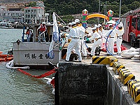 　工作人員利用吸油棉將船隻四周攔油索內的油汙吸起。（圖／文：曹重偉）