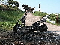 　福澳村福山公園入口昨天凌晨發生火燒機車意外，該車車頭佈滿泥濘，疑似棄置已久，起火原因尚在調查中。（圖／文：曹重偉）