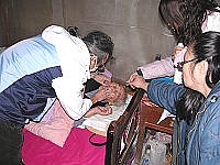 　長照中心辦理口腔篩檢到府服務，牙醫師夫婦林雅青及吳宏真專注的為一位依嬤查看假牙的咬合狀況。（圖／文：曹重偉）