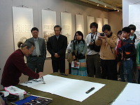 　縣府文化局主辦藝術與心靈之美巡迴展開幕典禮，藝術家曹楷智現場揮毫，現場來賓及師生凝神專注欣賞。（圖／文：劉秋月）