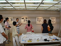 　中央研考會優質英語生活環境評核小組民俗文物館巧遇今天水墨展開幕的陳根彬，並親自解說畫作創意及思維。（圖／文：劉秋月）