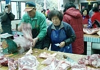賺錢手腳要快!傳統市場交易熱絡,攤販一邊收千元大鈔,一邊忙著為顧客包裝豬肉。目前馬祖各項農漁產品供應充裕,並且價格穩定。(圖/文:張登傑)